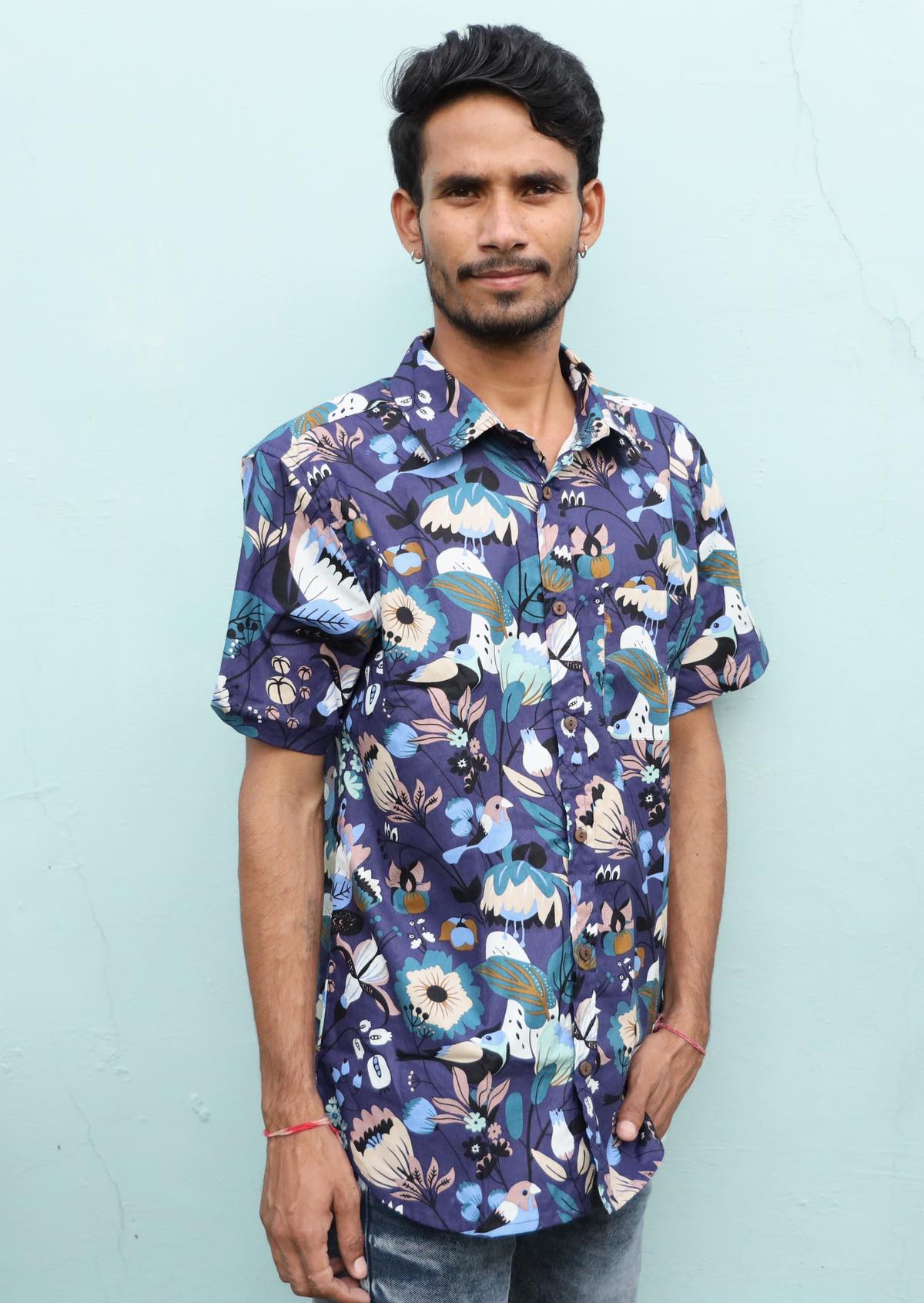 Man wears relaxed fit men's button through shirt with short sleeves in blue based floral print