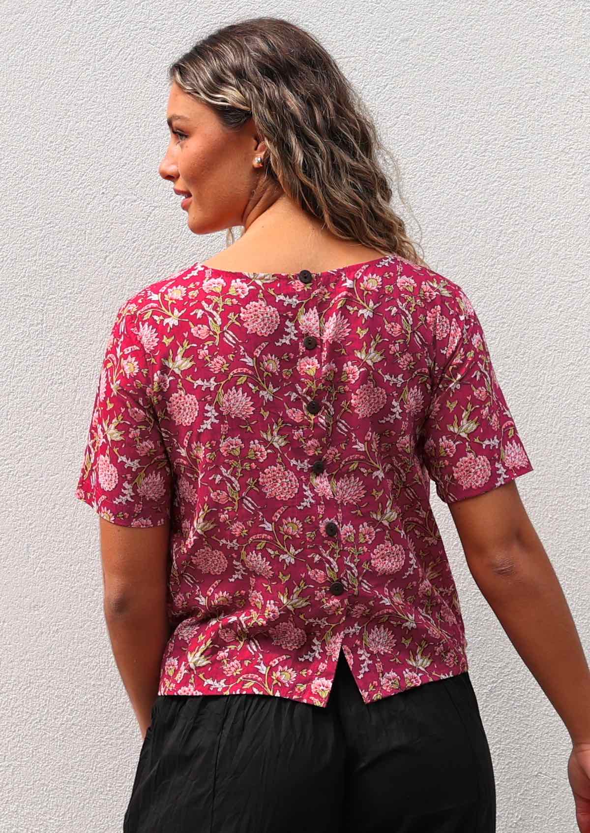 Back of woman in cotton short sleeve floral print top with decorative buttons down the centre of the back