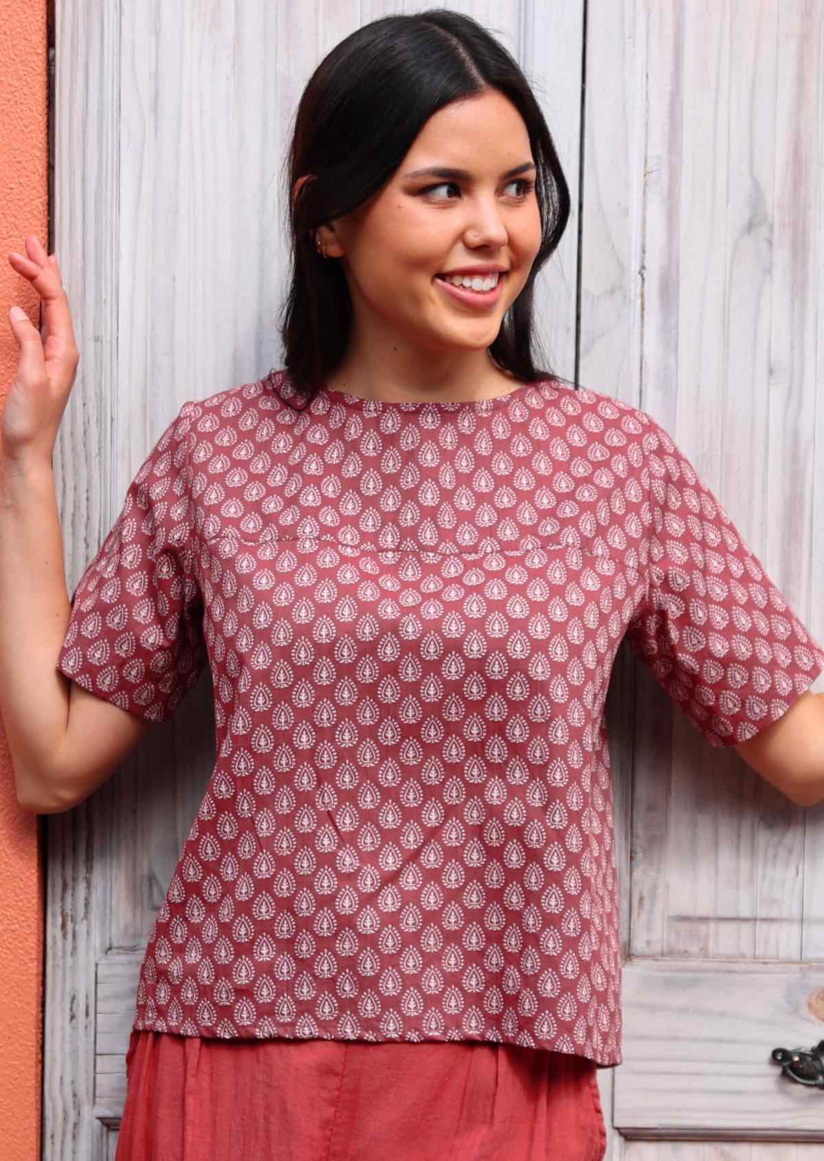 Woman wears relaxed fit 100% cotton top with round neckline and seam across chest in dark terracotta colour