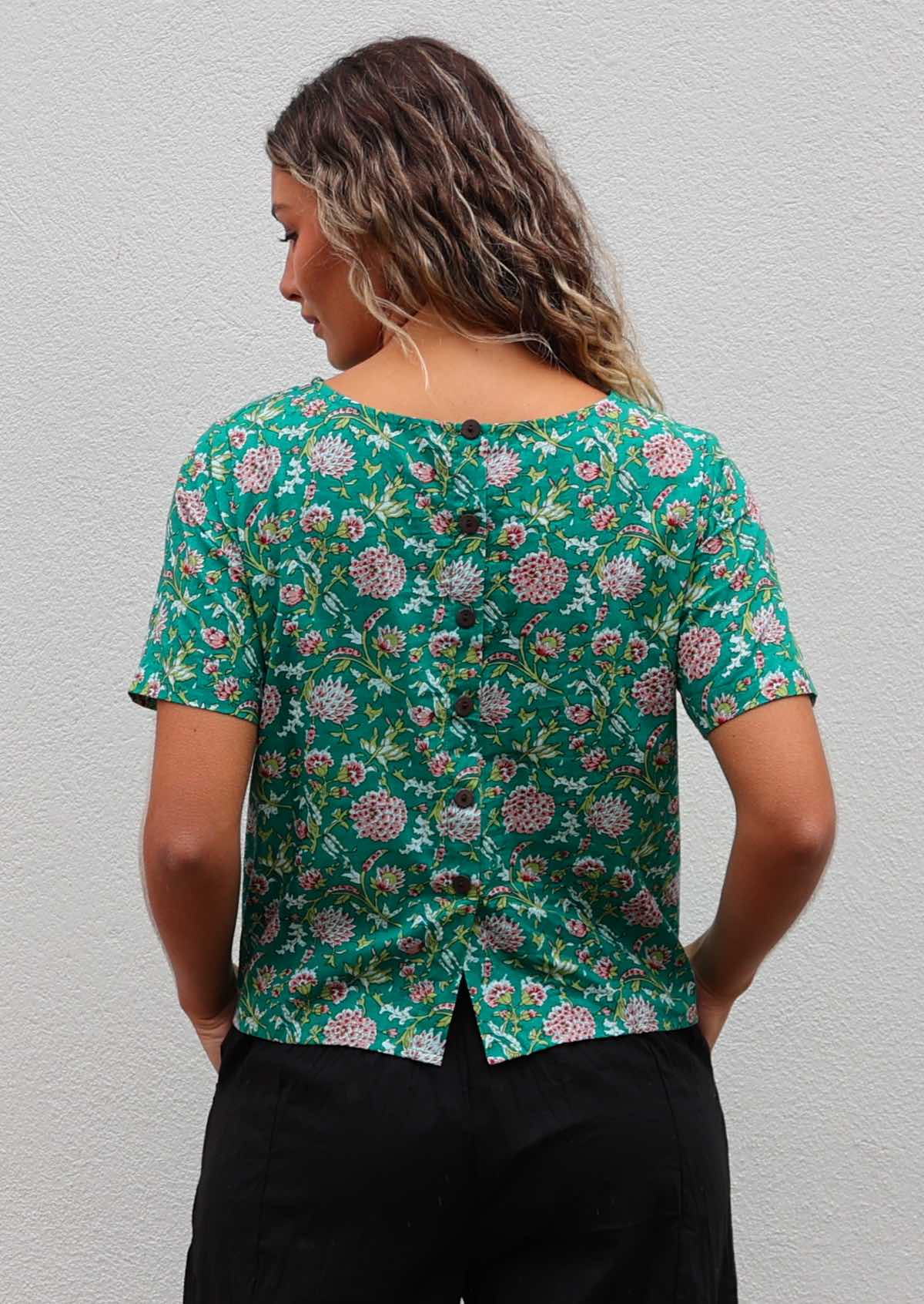 Back of model in 100% cotton short sleeve top with decorative buttons down the centre of the back