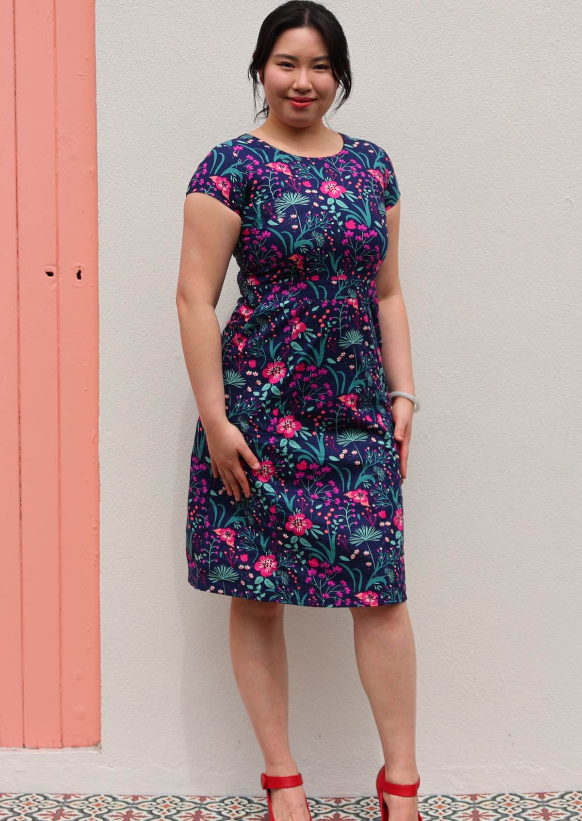 woman in navy pink and purple floral cotton knee length dress with round neckline empire waist