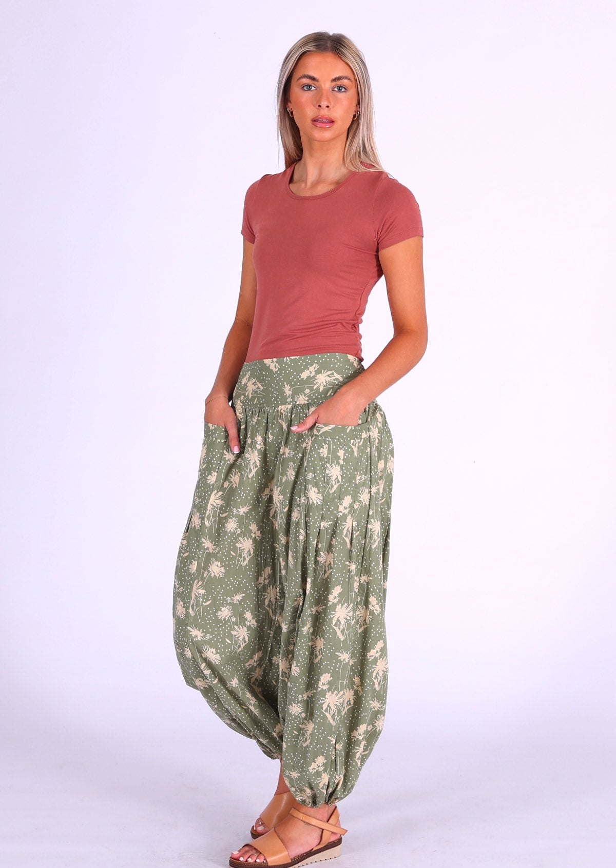 Woman stands in cotton harem pants with wide flat front waistband with her hands in pockets