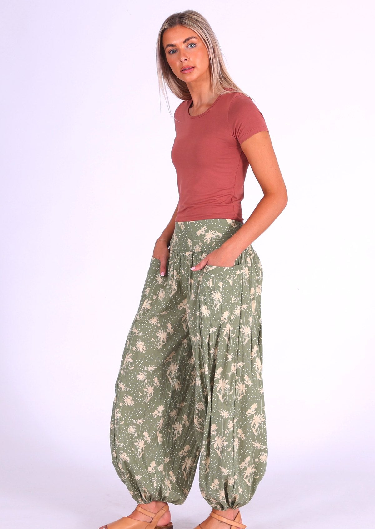 Model wears cotton harem pants in pale green and cream floral print with her hands in pockets