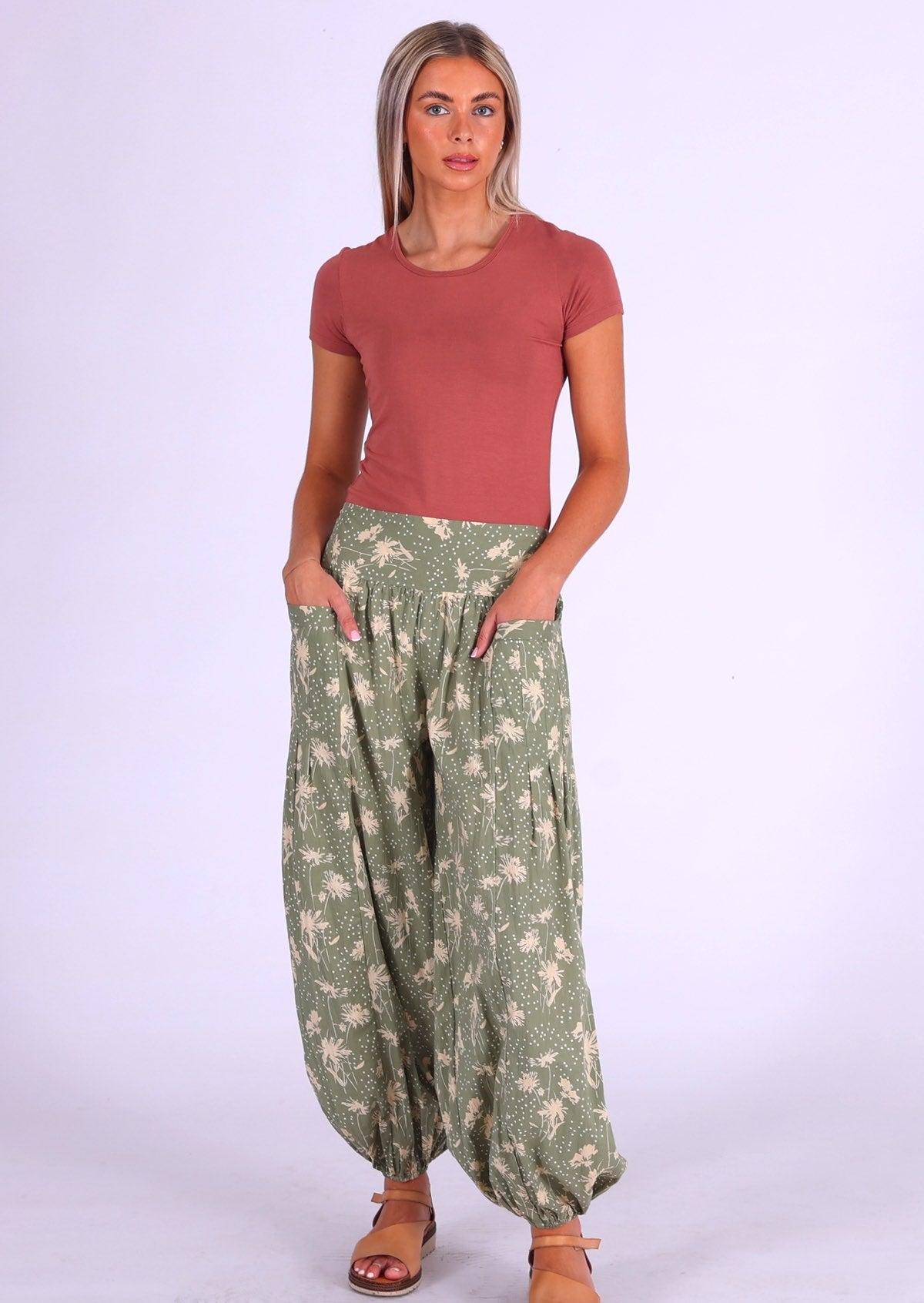 Woman wears cotton wide leg pants with elasticated ankles and wide flat front waistband with het hands in pockets