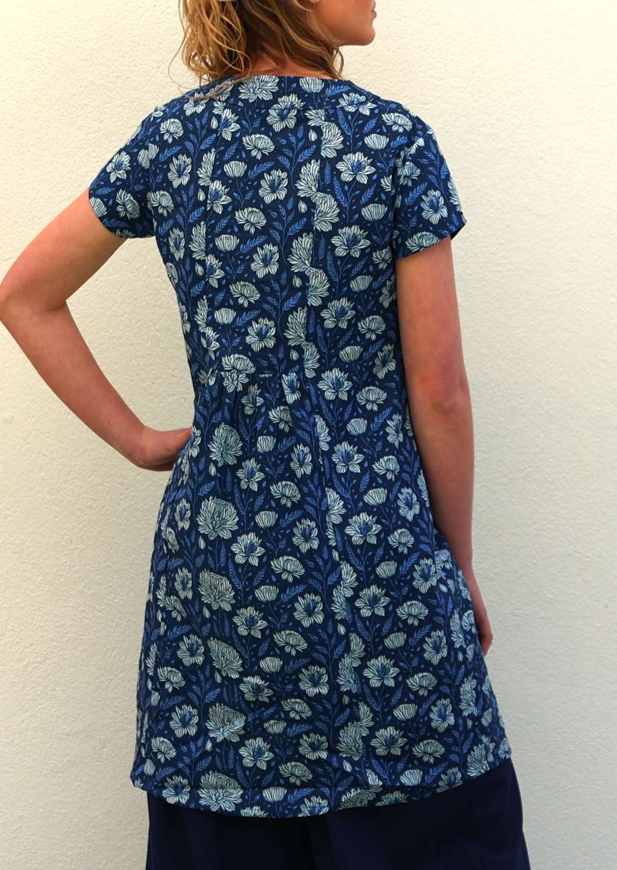 Back of model in blue floral print cotton tunic dress with short sleeves