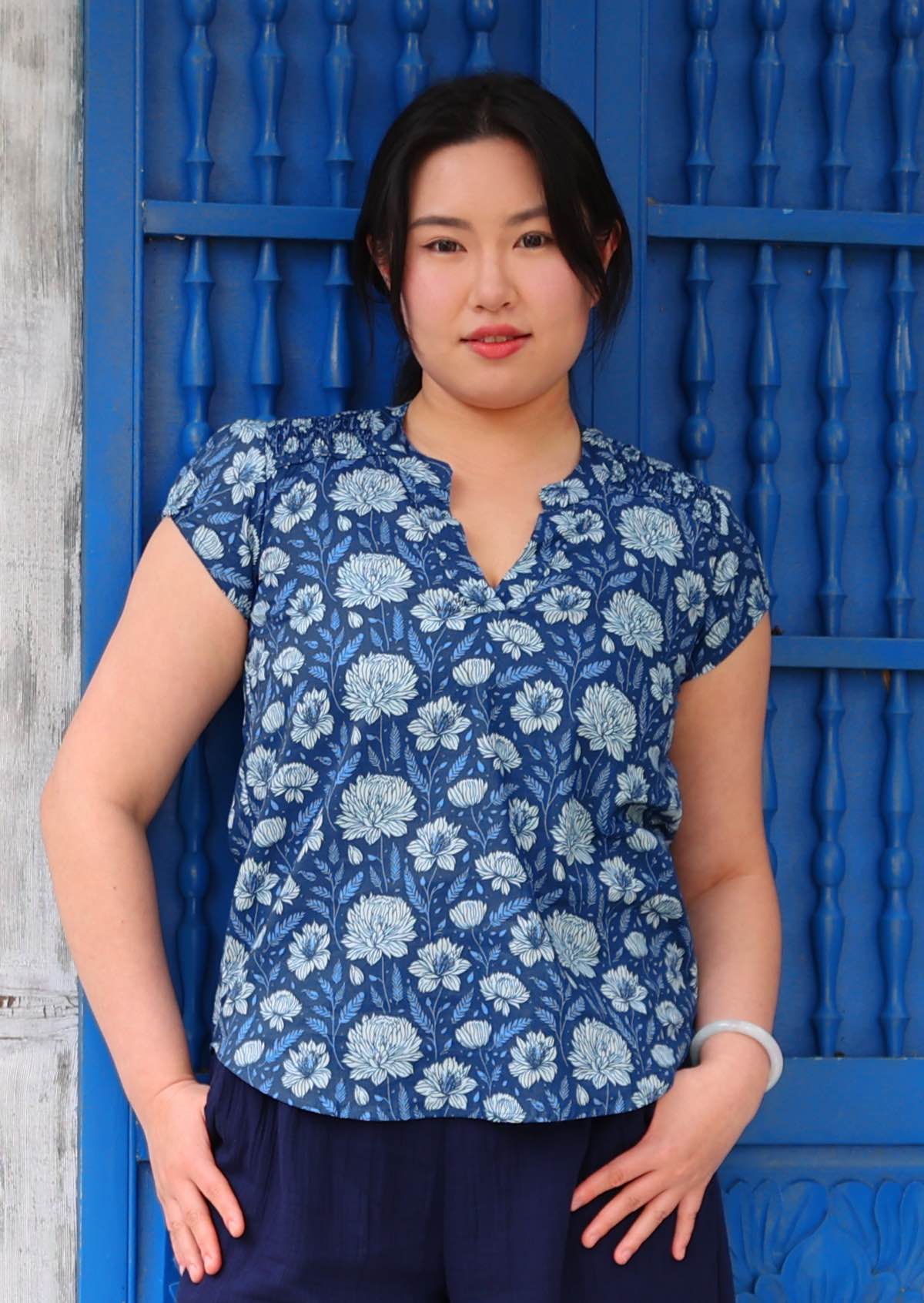 Woman in cotton top with cap sleeves and V-neckline with mandarin collar in blue floral print