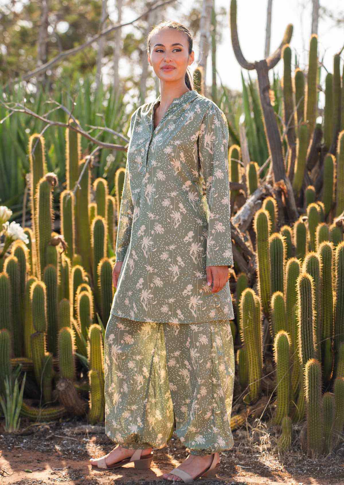 Woman stands in long sleeve cotton tunic with matching print harem pants, both with cream floral pattern on pale green base