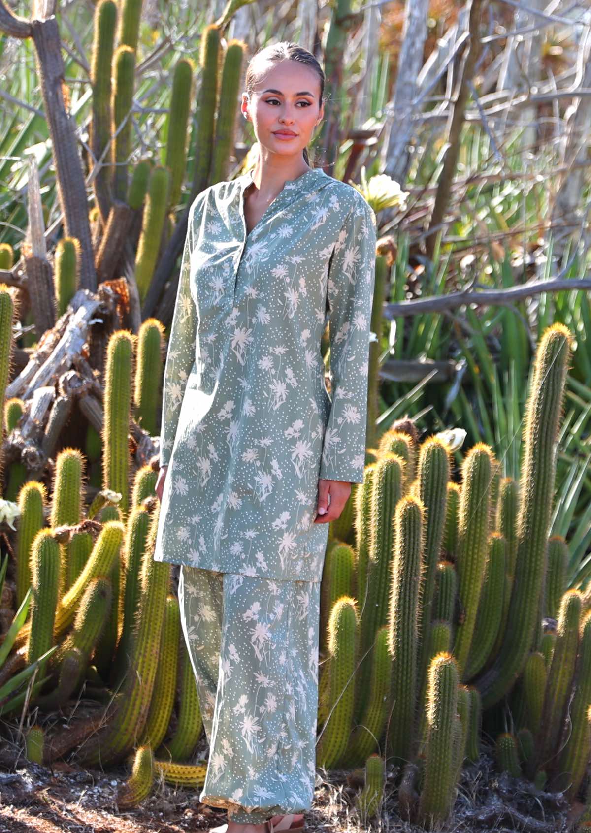 Woman wears cotton long sleeve tunic with two buttons and mandarin collar, in pale green based floral print