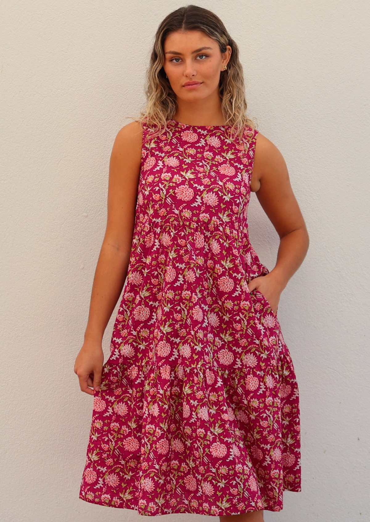 Woman in cotton sleeveless dress with high round neckline, holding skirt out to indicate volume