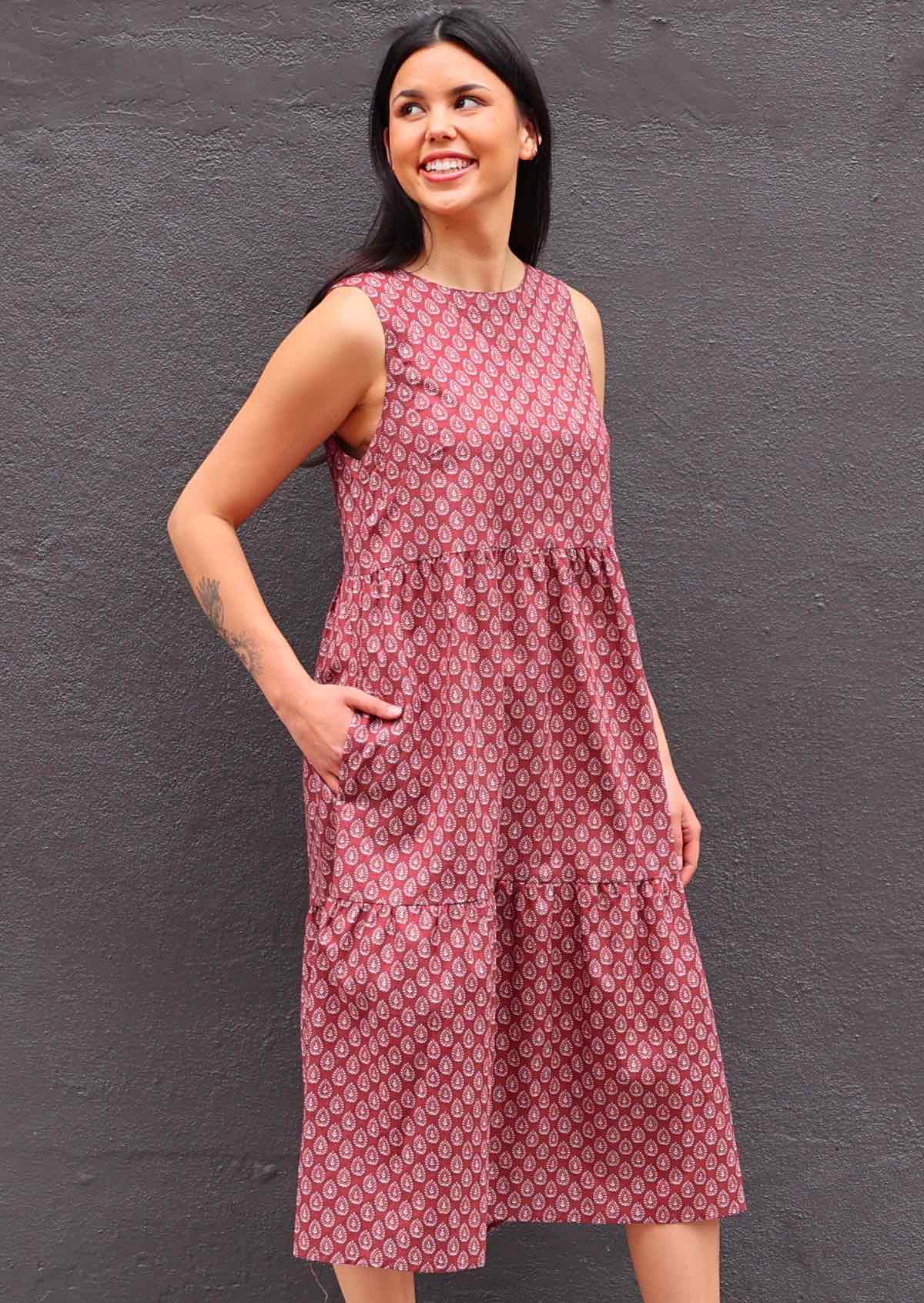 Woman with dark hair in Indian Cotton Sundress with three tiers hand in pocket in front of dark grey wall