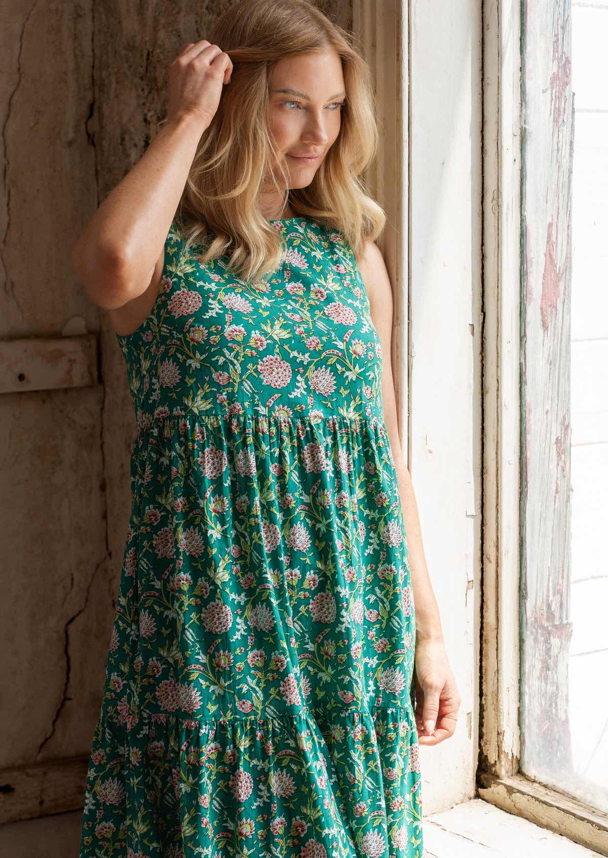 Close up of woman in cotton sleeveless dress in sweet floral print on a jade green base