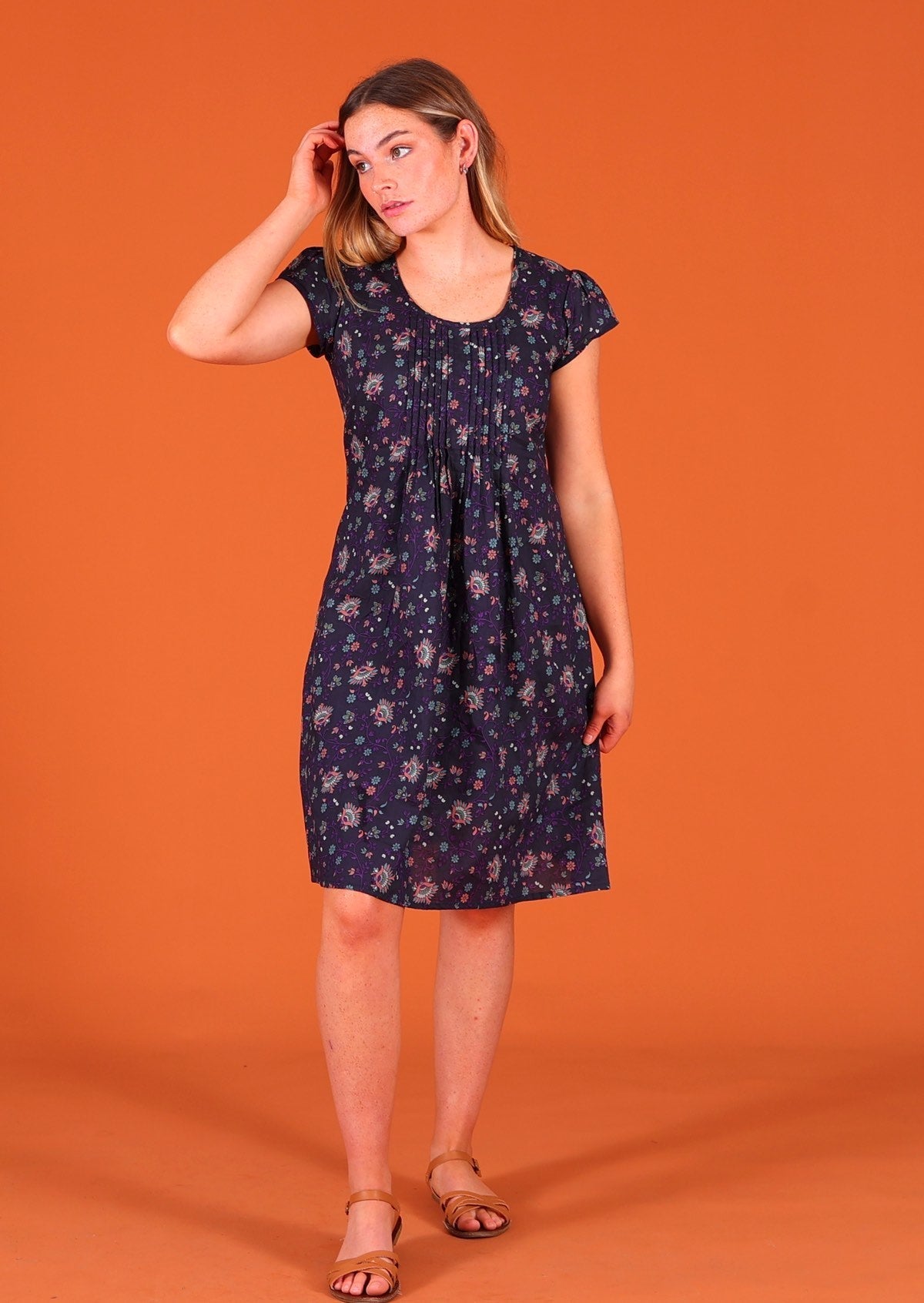 Model standing wearing 100 percent cotton short sleeve pleated above knee sundress in deep purple Indian floral