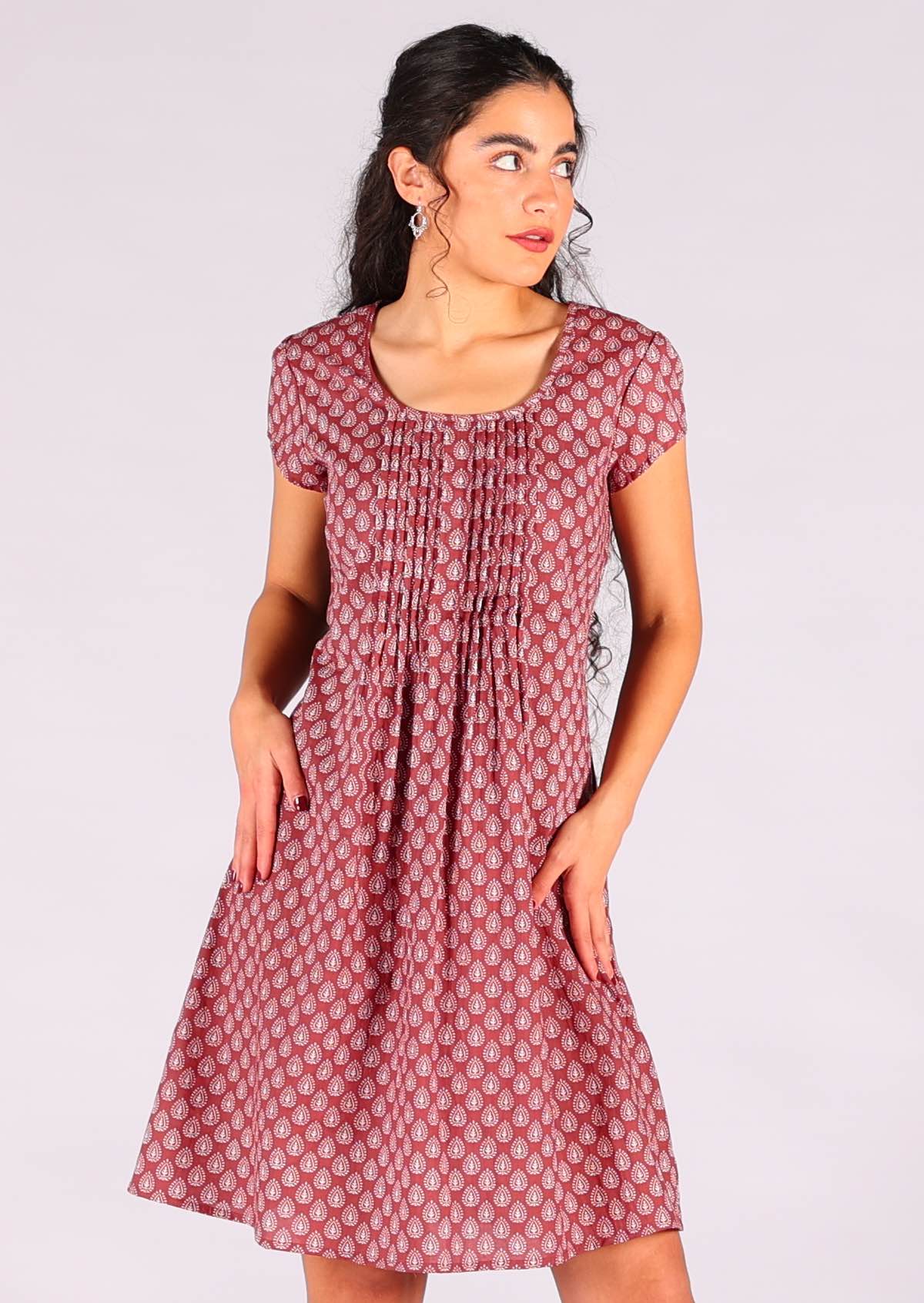 Model standing wearing 100 percent cotton short sleeve pleated above knee sundress in dark terracotta 