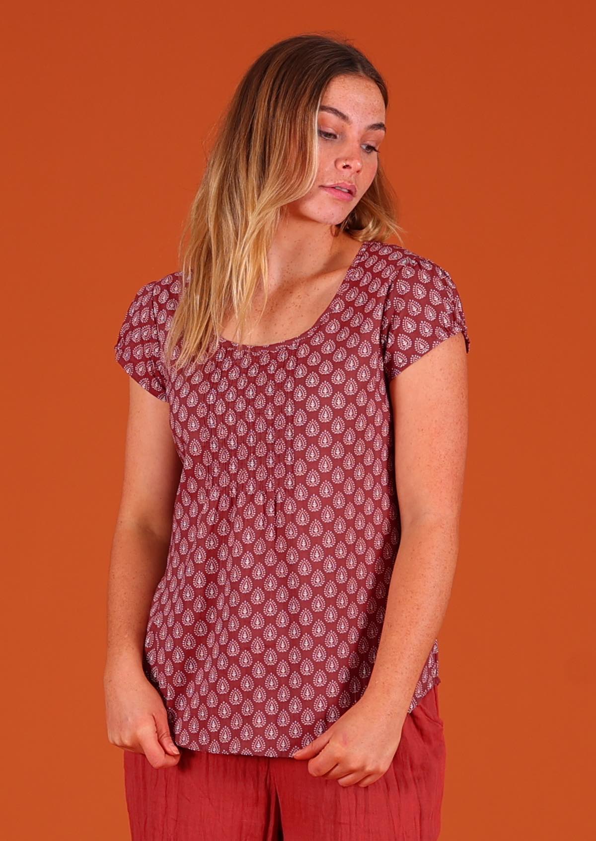 Model facing to the side wearing 100 percent cotton Indian block print short sleeve pleated blouse dark terracotta