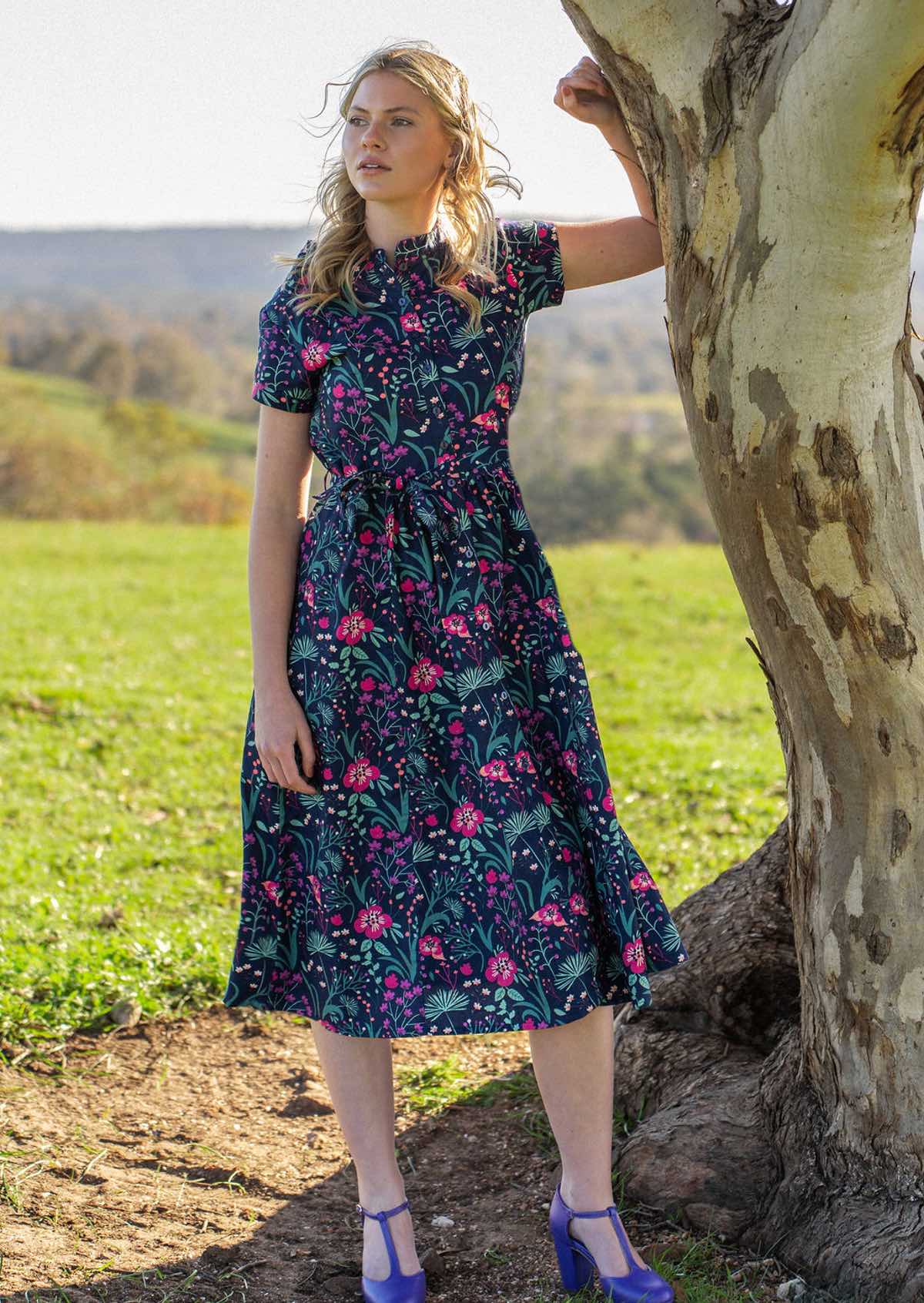 Woman standing under tree in Navy cotton floral maxi dress with belt 