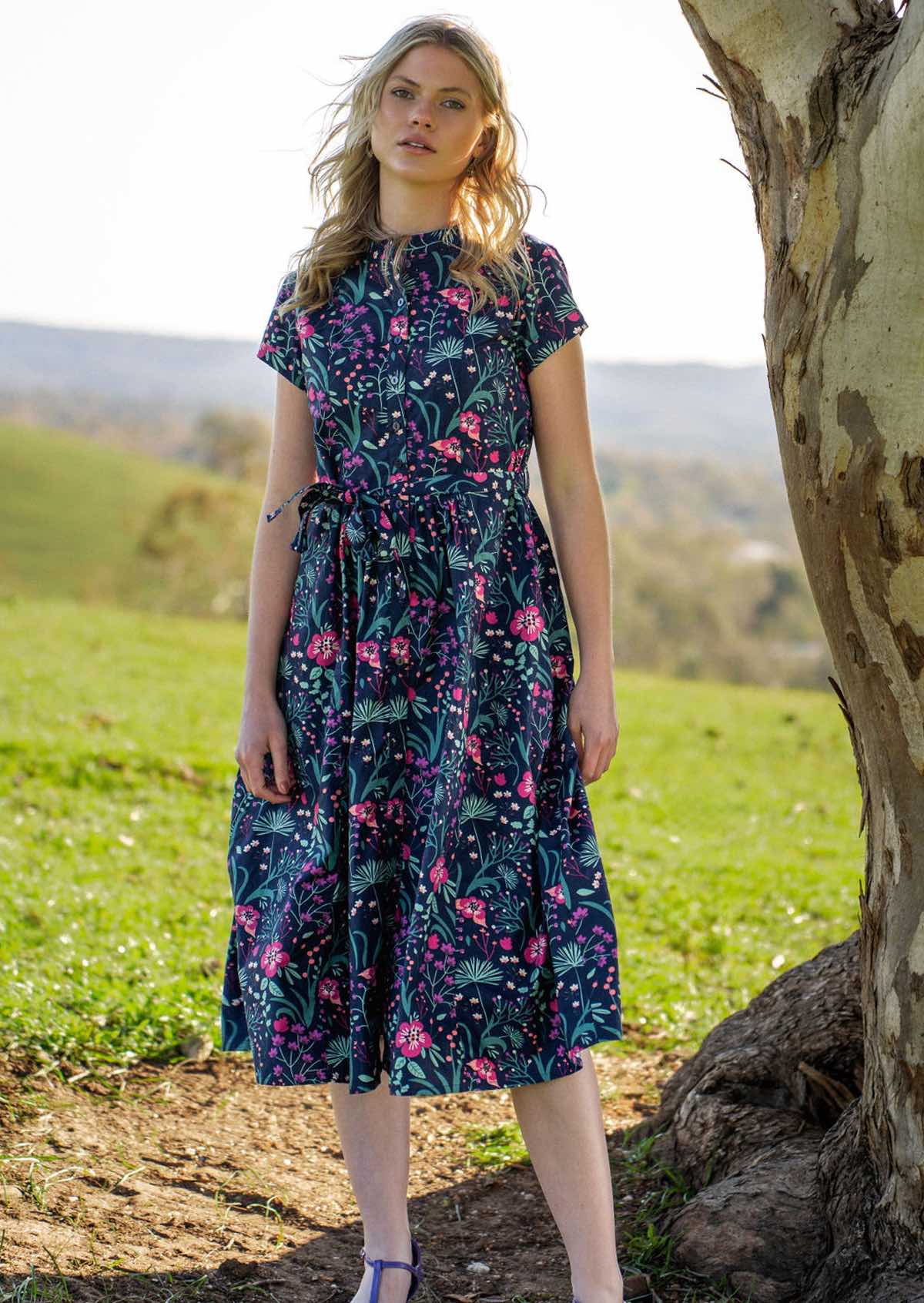 Woman standing under tree in Navy cotton floral maxi dress with pockets
