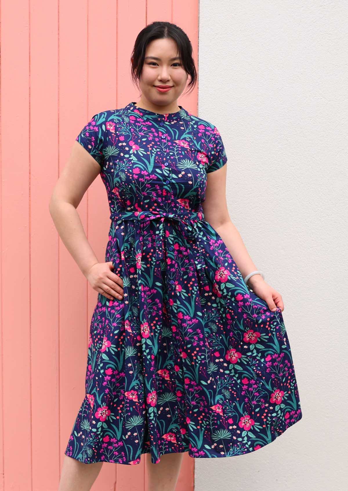 Woman standing in Navy cotton floral maxi dress with v-neck and  pockets 