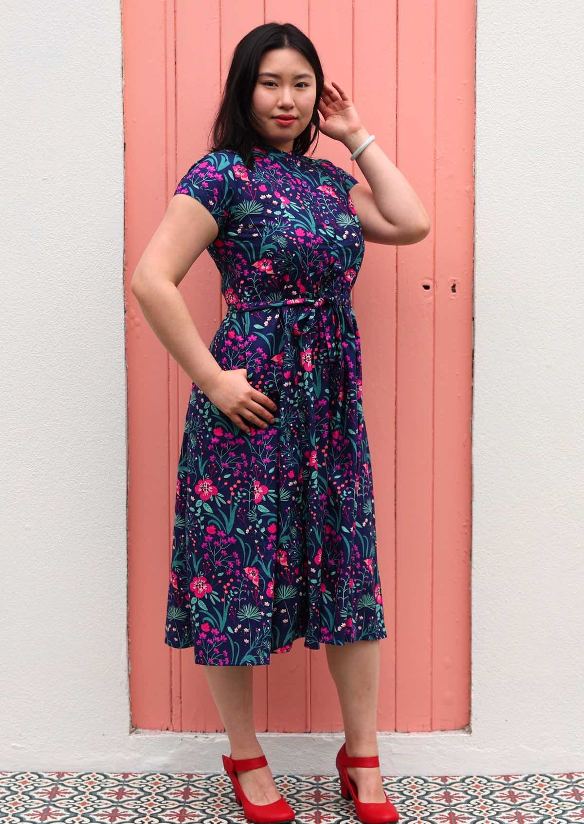 Woman standing in Navy cotton floral maxi dress with v-neck wearing red shoes