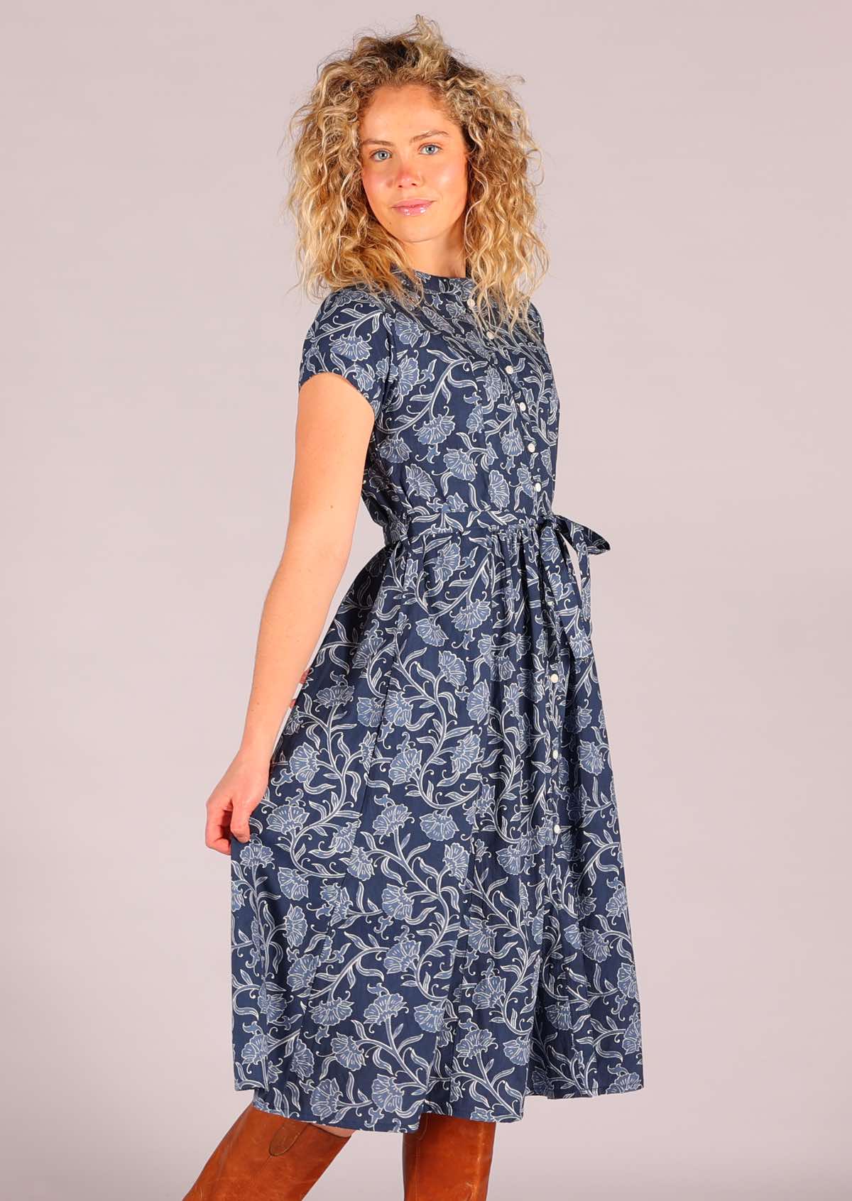 Woman modelling 100 percent cotton retro shirt dress with pockets and waist tie in floral and navy blue background