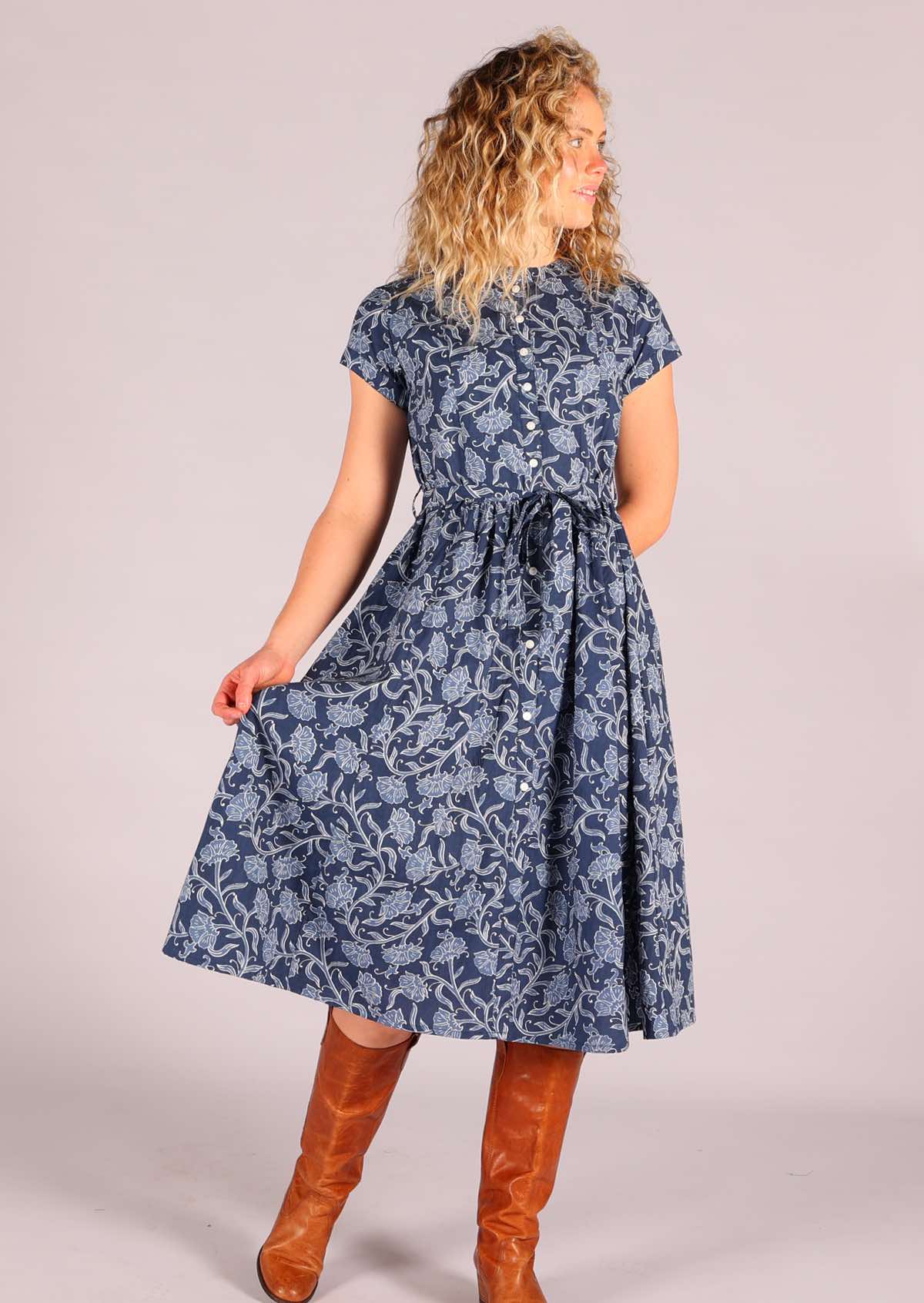 Model standing wearing 100 percent cotton retro shirt dress with pockets floral navy blue background