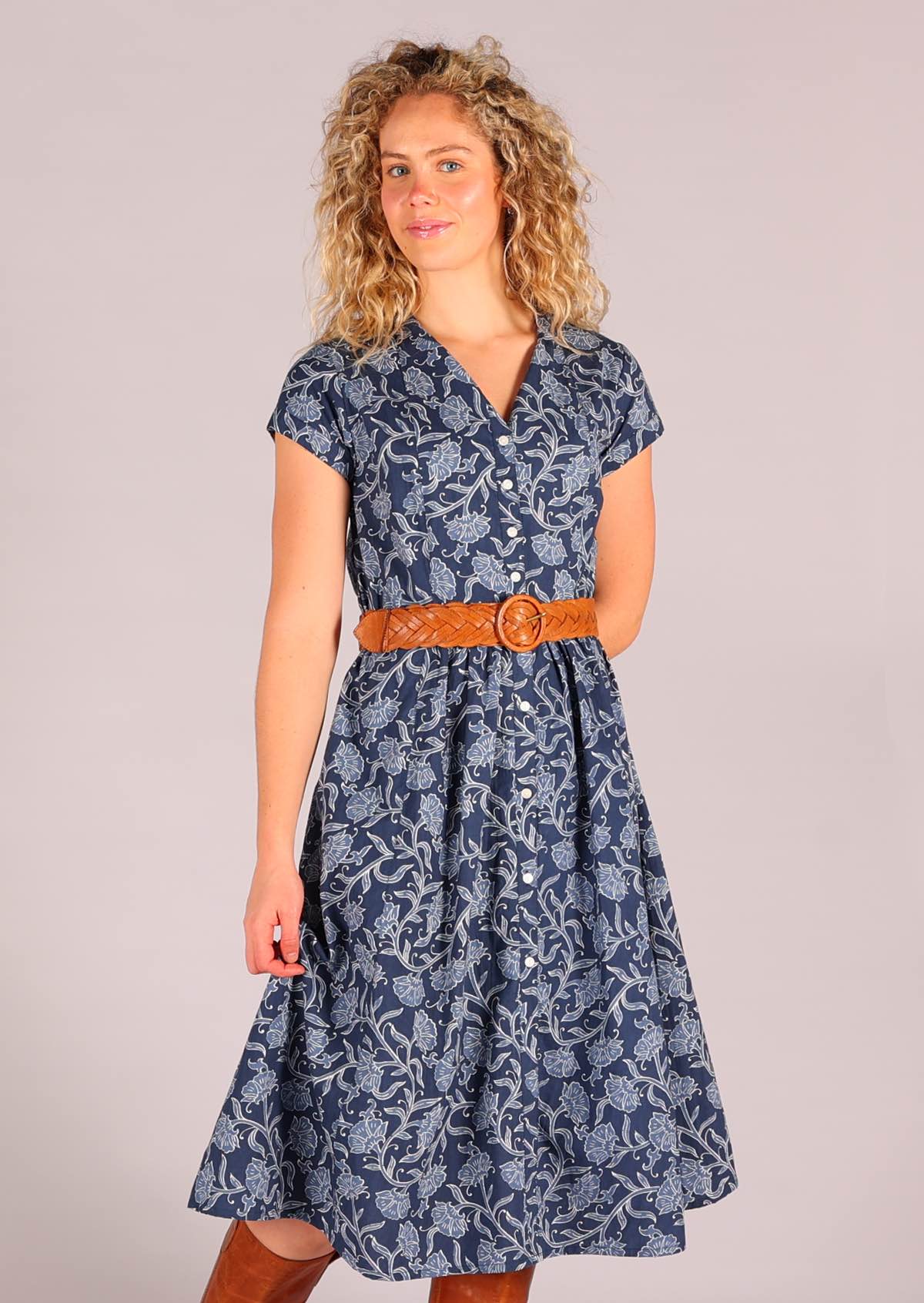 Model standing wearing 100 percent cotton Navy blue retro button down shirt dress with pockets and tan leather waist belt 