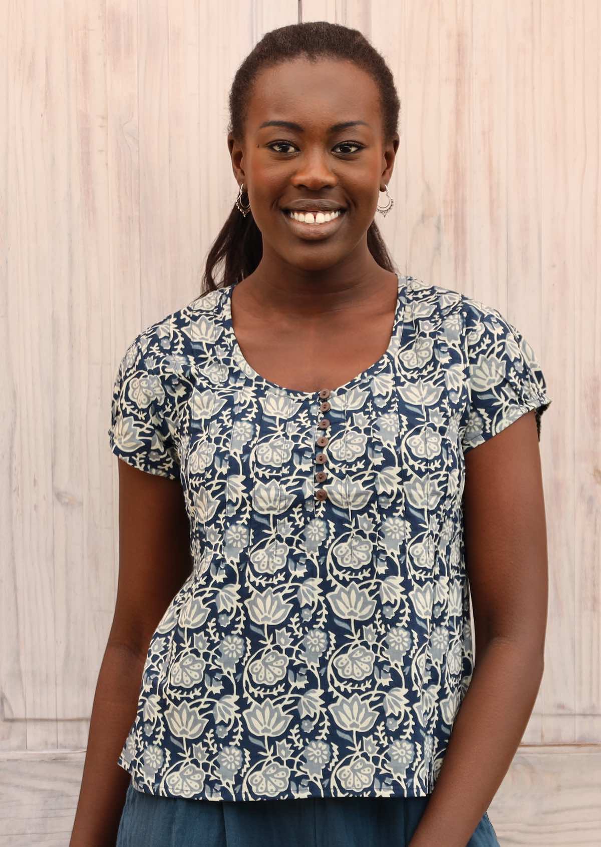 Model wears top that has a blue base and a white floral pattern. 