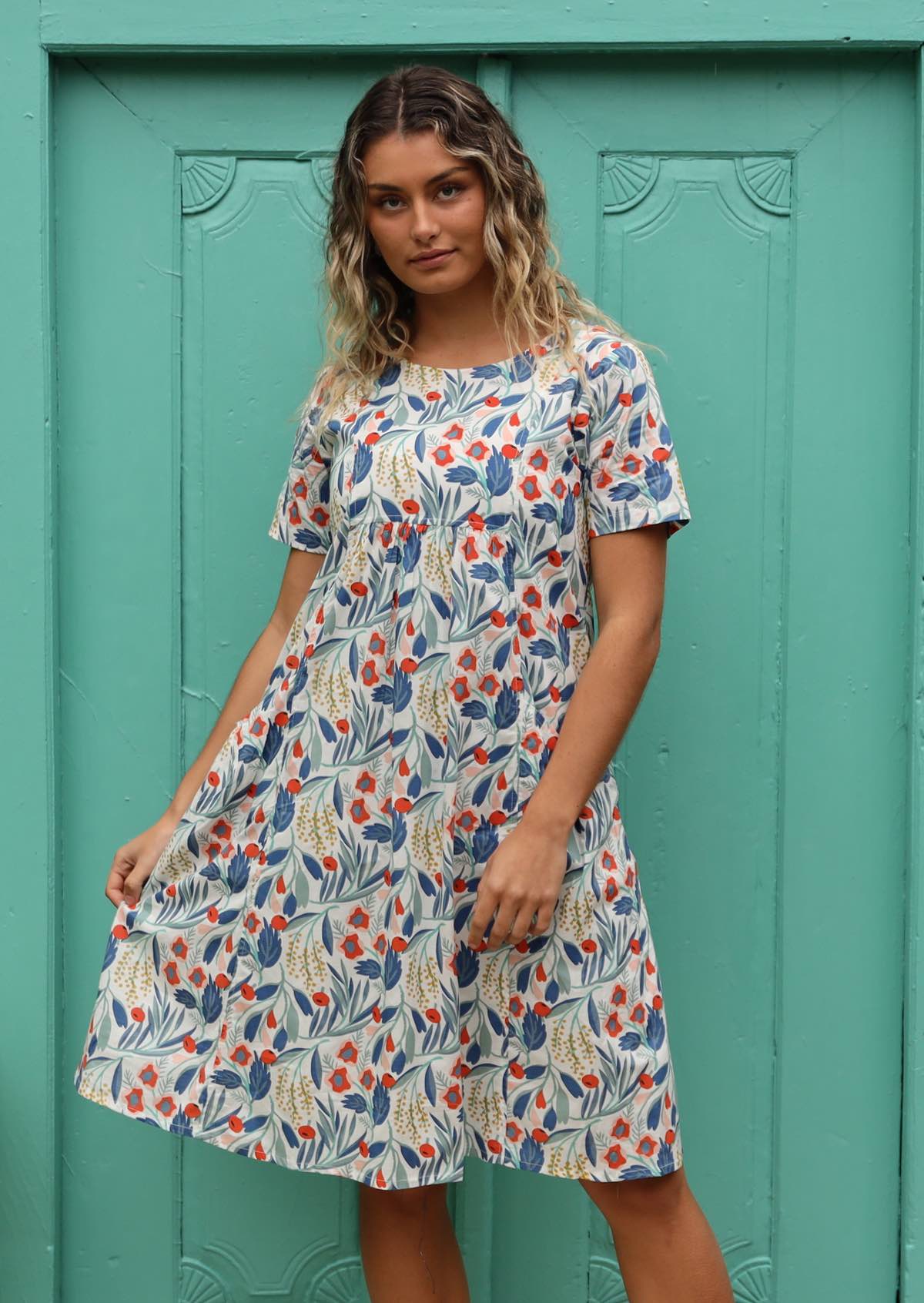 Model wears a loose fitting dress with a square yolk bib. 